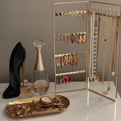 gold jewelry and shoes are sitting on a white table next to an open case with several necklaces in it