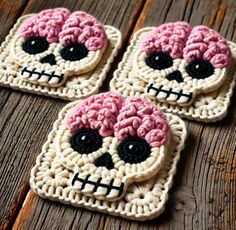 three crocheted sugar skulls sitting on top of a wooden table