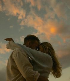 a man and woman are standing under the cloudy sky with their arms around each other