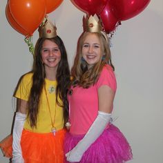 two girls dressed up in costumes posing for the camera with balloons and crowns on their heads