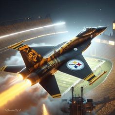 a fighter jet flying through the air over a football field with lights in the background