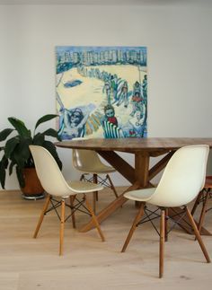 a dining room table with four chairs and a painting on the wall