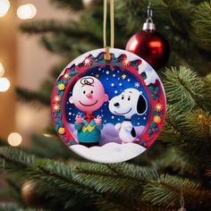 a christmas ornament hanging from a tree with two dogs on it's side