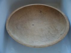 a wooden bowl sitting on top of a white tablecloth covered floor next to a blue wall