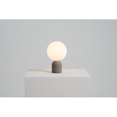 a white table lamp sitting on top of a block