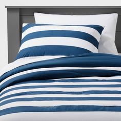 a blue and white striped comforter on a bed with two pillow cases in front of it