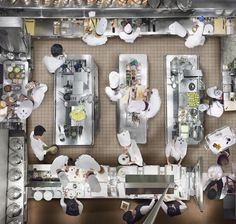 an overhead view of a kitchen with chefs preparing food in the center and on the wall