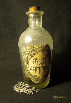 an empty glass bottle sitting on top of a black table next to some white flowers