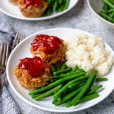 two white plates topped with meatballs and green beans next to mashed cauliflower