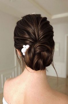 a woman with her hair in a low bun and two small pins on the back of her head