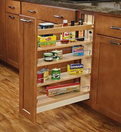 an open pull out spice rack in a kitchen with wood flooring and wooden cabinets