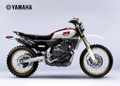 a white and black motorcycle parked in front of a gray background with the words yamaha on it