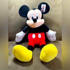 a mickey mouse stuffed animal sitting on top of a couch