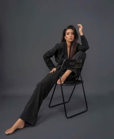 a woman sitting in a chair with her hand on her head and one foot up