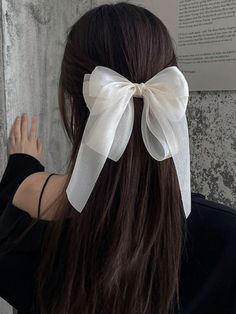 a woman with long brown hair wearing a white bow