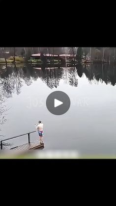 a man standing on a dock next to a body of water with trees in the background