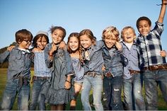 a group of young children standing next to each other on top of a grass covered field