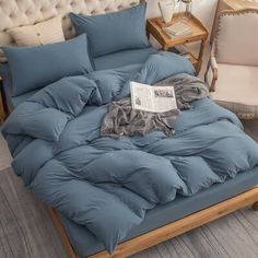 an unmade bed with blue comforter and pillows on it in a living room