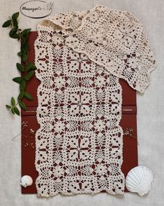 crocheted doily and seashells are laid out on a piece of cloth