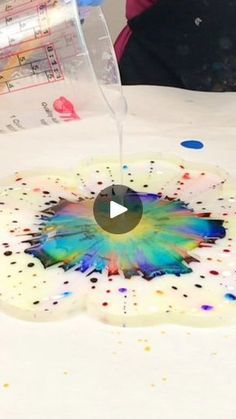 someone is pouring water into a plate with paint splattered all over the surface