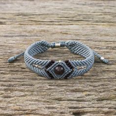 the bracelet is made with blue seed beads and brown bead, on top of a wooden table