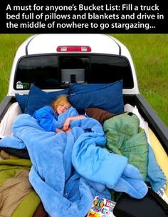 a woman is sleeping in the back of a truck with blankets and pillows on it