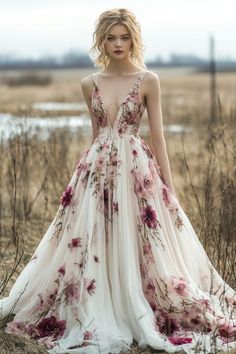 a woman is standing in a field wearing a dress with flowers on it