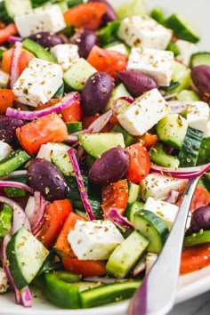 a white bowl filled with cucumber, red onion and feta cheese salad