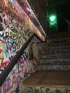 graffiti painted on the walls and stairs in an abandoned building with green light at the top