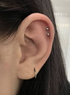 a woman's ear with two piercings on it