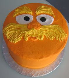 an orange cake with yellow frosting and googly eyes on it's face