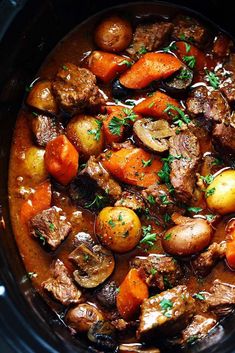 a crock pot filled with beef and potatoes, garnished with parsley