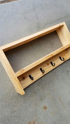 a wooden shelf with three hooks on it