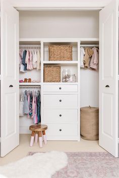 a white closet with clothes and baskets on the shelves