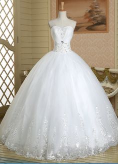 a white ball gown on display in a room with wooden flooring and wallpaper