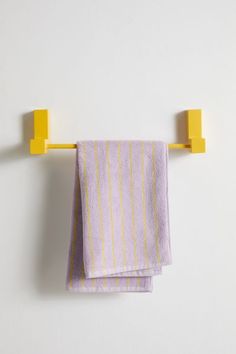 two towels are hanging on the wall with yellow hooks and one is folded in half