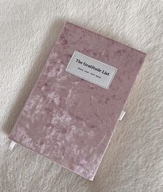 a pink book sitting on top of a white blanket