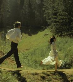 a man and woman running across a dirt road