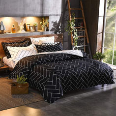 a bed with black and white comforter next to a wooden ladder in a room