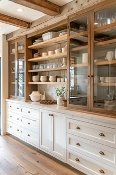 a kitchen with white cupboards and wooden shelves filled with dishes on top of them