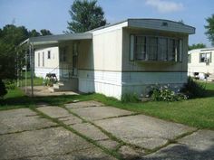 an old mobile home sits in the grass