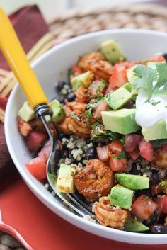 a white bowl filled with shrimp, avocado and rice