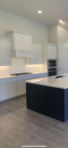 a large kitchen with an island in the middle and white cabinets on both sides is shown