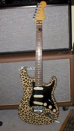 an electric guitar sitting on top of a carpeted floor next to two amps