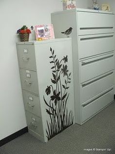 a filing cabinet with flowers painted on the front and side, next to a wall decal