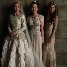 three women in white dresses standing next to each other wearing tiaras and veils