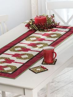 a white table with a red candle on top of it and a quilted table runner