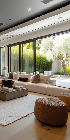 a living room filled with lots of furniture next to large glass windows on the wall