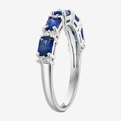 a three stone ring with blue sapphires and diamonds on the sides, set in 18k white gold