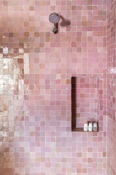 a bathroom with pink tiles on the shower wall